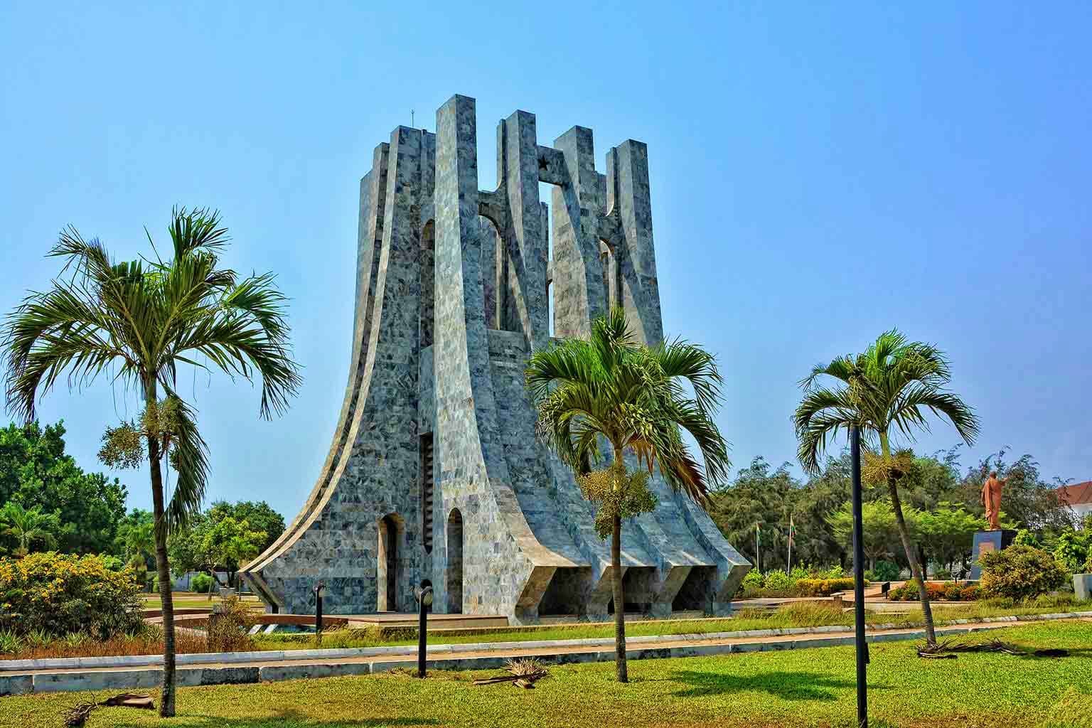 Ghana Visa Kwame Nkrumah Mausoleum in Accra, Ghana - a concrete monument with tall vertical columns and palm trees surrounding it under